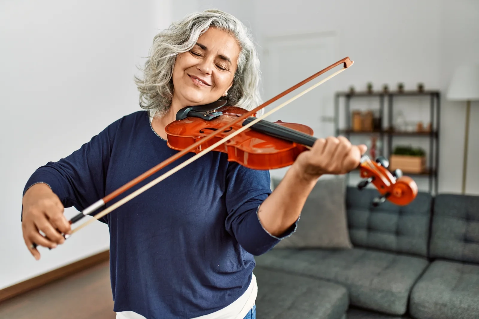 An happy and smiling elderly women playing a violin