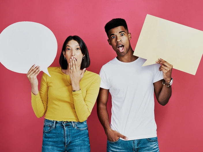 Image of 2 people with cardboard cutouts in form of question bubble